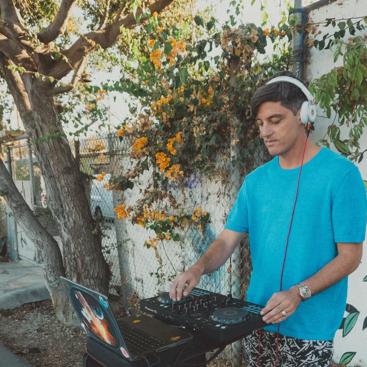 Magmatic DJing outdoors beside flowering vines